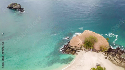 A top-down drone shot of an idyllic Koka Beach. Hidden gem of Flores, Indonesia. Headland going straight into the open sea. Beauty in the nature. Calm waves washing the cliff's slopes. Serenity. photo