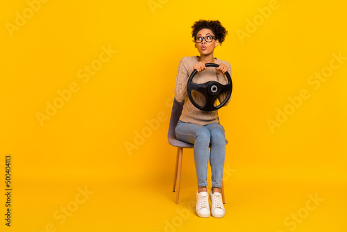 Full body photo of young girl sit stool interested look empty space vehicle trip isolated over yellow color background