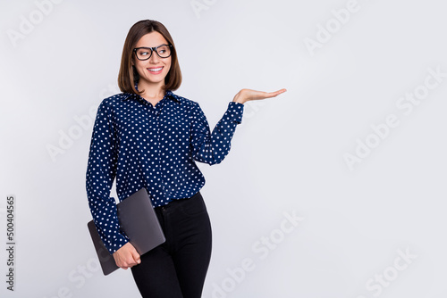 Portrait of beautiful trendy cheerful girl with laptop holding ad copy blank space isolated over grey pastel color background