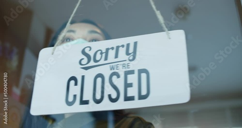 Asian young woman wear a mask worker slide the door to close the shop.Small businesses that have to close their shops due to the coronavirus pandemic.Focus on the closed shop sign.New normal lifestyl. photo