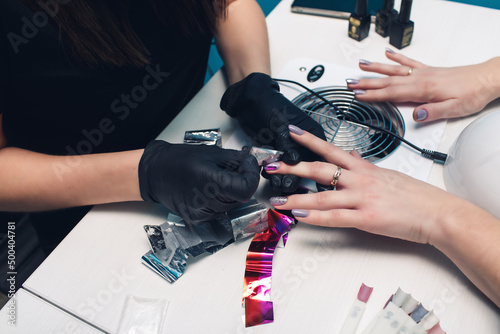 manicure process in a beauty salon. color transfer from foil to nails