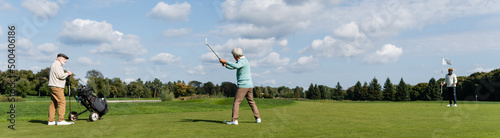 senior asian man playing golf near friends with flag stick and golf cart, banner.