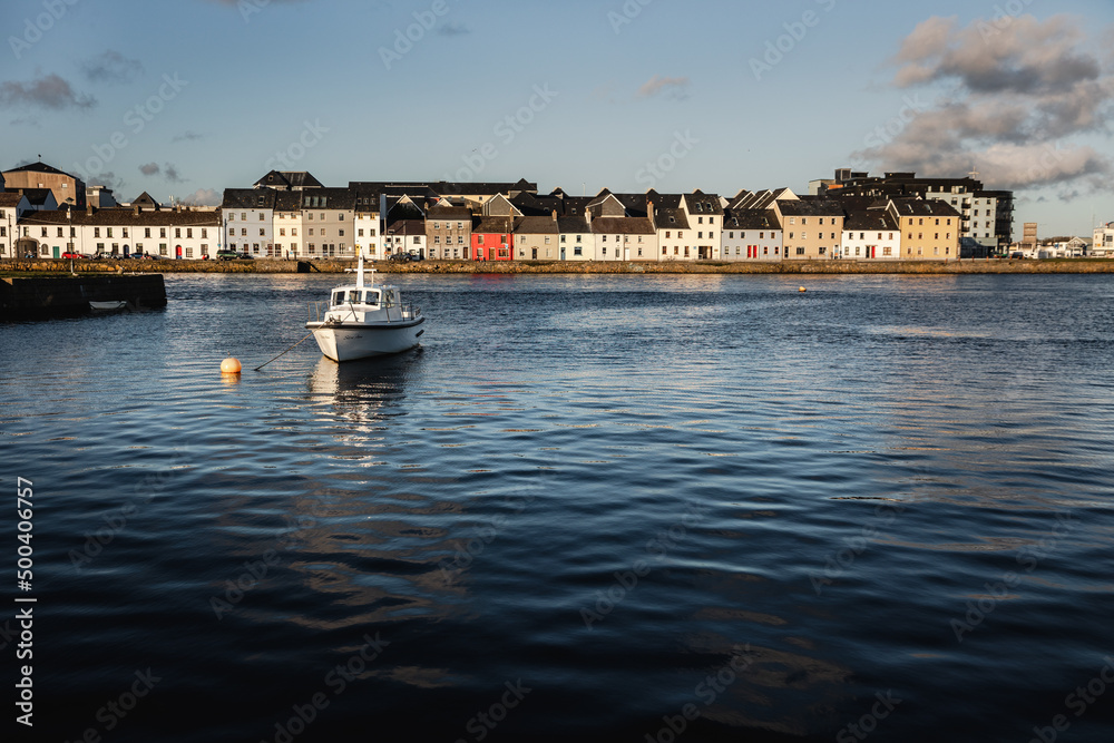 Fototapeta premium Old wooden shipwrecks in Claddagh Bay, Galway, sunny day in beautiful and popular tourist spot with colourful houses in the background and waters of Atlantic Ocean - best Ireland