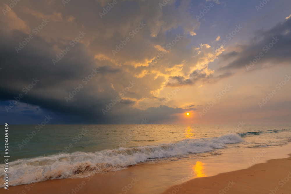 Gorgeous sunset sky with clouds over Indian ocean sandy beach with a foamy wave. Beautiful seascape.