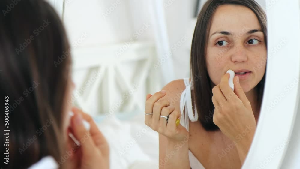 Young adult woman looking at herself in the mirror and applies hygienic lipstick or lip balm. In the morning routine concept, close-up 4k footage Young adult woman looking at herself in the mirror and applies hygienic lipstick or lip balm. In the morning routine concept, close-up 4k footage