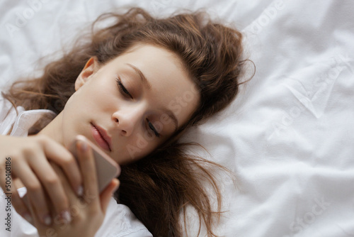 close up Portrait of the girl lying on bed with mobile phone