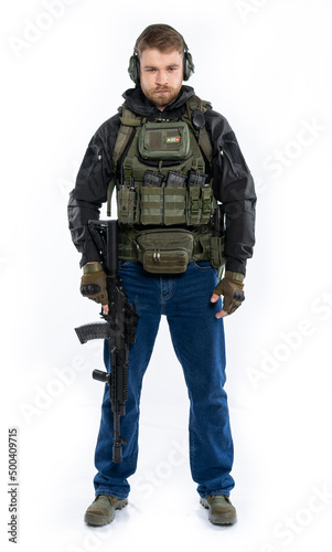 soldier, airsoft player in full gear with a machine gun. a man in headphones, a bulletproof vest, with a backpack and a full-length belt. White background.