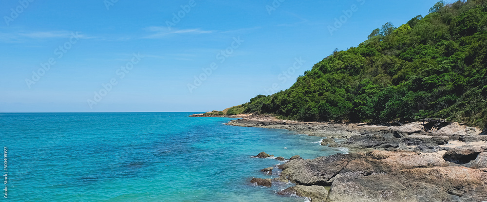Rocks on the tropical beach landscape. Natural seashore in summertime. Coastline seascape on sunny day. Bright blue sky and turquoise water. Island scenery.