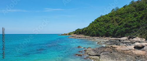 Rocks on the tropical beach landscape. Natural seashore in summertime. Coastline seascape on sunny day. Bright blue sky and turquoise water. Island scenery.