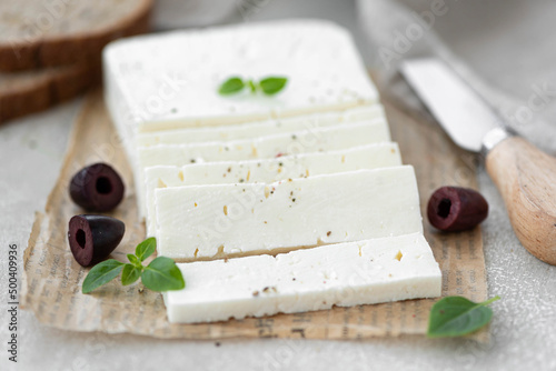 homemade feta cheese with olives and herbs on a wooden table photo
