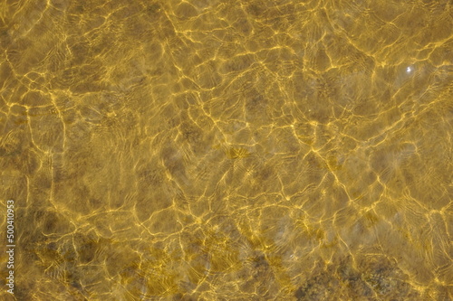 Amber Colored Ripples of Water Over Clay as Background