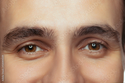 Cropped close-up portrait of beautiful male brown eyes looking at camera. Calm, attentive look.