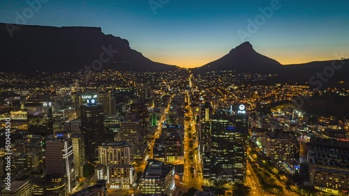 Evening aerial hyperlapse shot of downtown. Silhouette of mountain ridge in background. South Africa