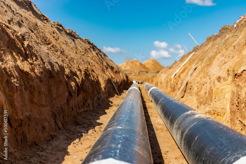 Insulated pipe. Large metal pipes with a plastic sheath laid in a trench. Modern pipeline for supplying hot water and heating to a residential area.