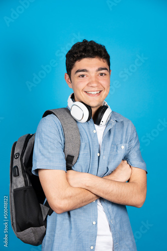 Smiling hispanic college student looking at camera isolated on blue background.