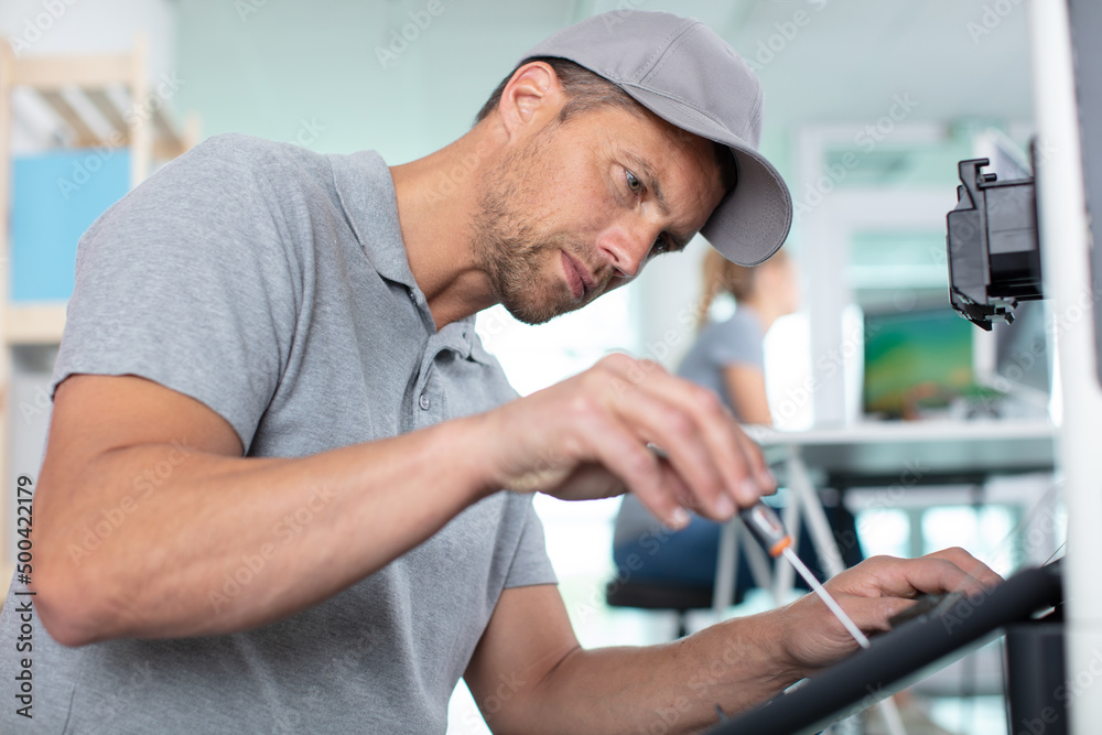 Fototapeta premium young male technician is repairing a printer at office