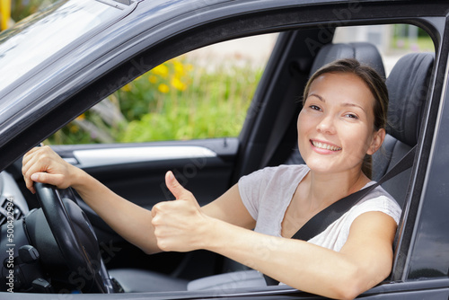 young female driver behind the wheel making thumbs up gesture