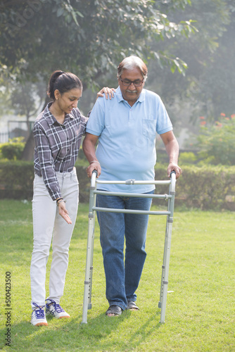 Senior citizen man use a walker in the park with granddaughter. © G-images