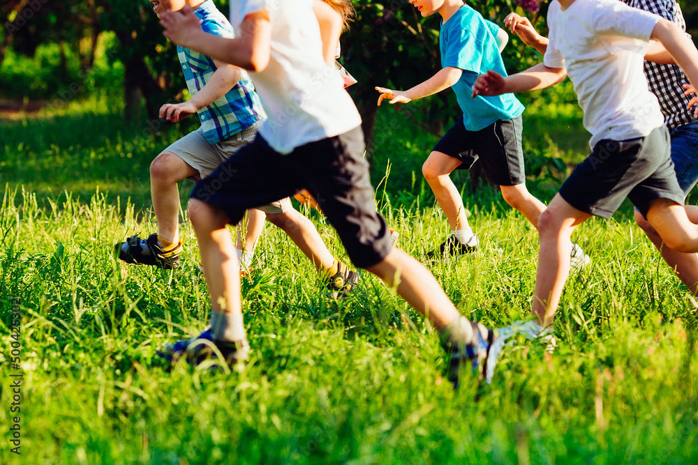 Fototapeta premium Close up of kids legs run down on the grass field.