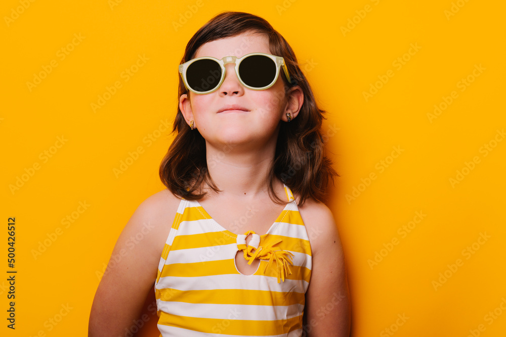 Stylish girl in sunglasses standing in studio Stylish girl in sunglasses standing in studio