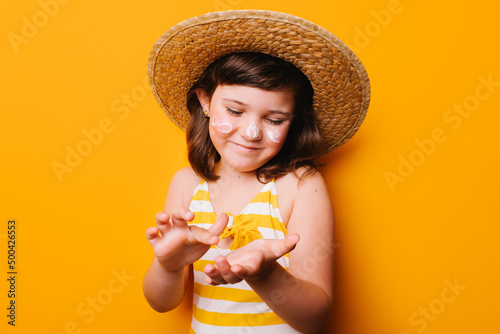 Girl applying suntan cream of face