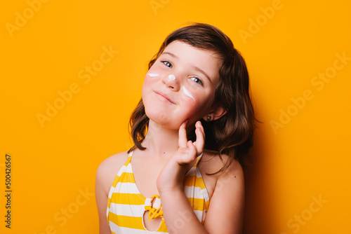 Girl applying suntan cream of face photo