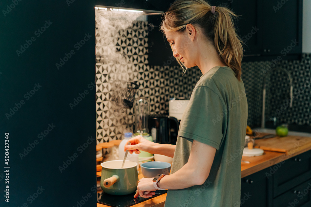 Young woman prepping and cooking in small city kitchen Young woman prepping and cooking in small city kitchen