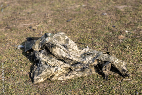 Burned and torn piece of Ukrainian army soldier's pixel camouflage military uniform who died in the village during battle in tank. War of Russia against Ukraine. Concept of invasion and genocide. 