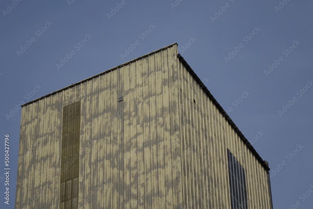 Cubic metal tower of factory building under blue spring sky, concept: industry, industrial (horizontal), Seltz, Grand Est, France