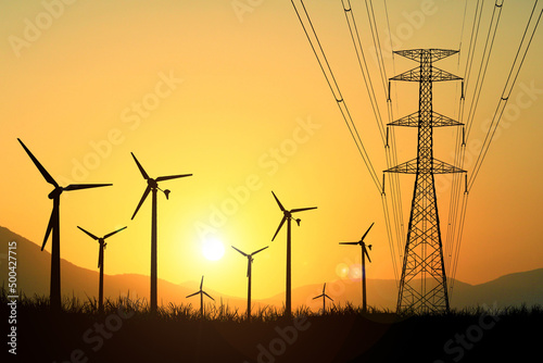 Wind turbine silhouettes are used to generate electricity in the fields during the evening hours.