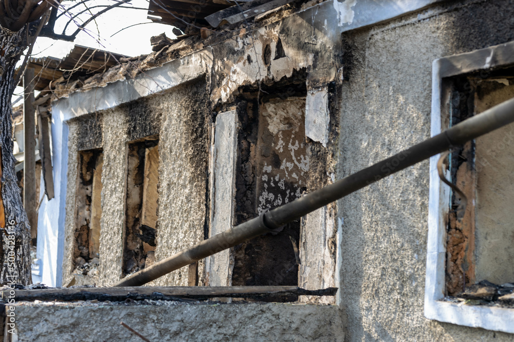 Barmashovo, Ukraine- March 18, 2022: War of Russia against Ukraine. Concept of invasion. Burned and demolished house in the center of a  village. Holes in the wall instead of window.  