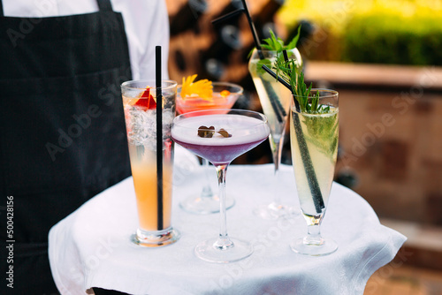 The waiter serves cocktails on a tray. photo