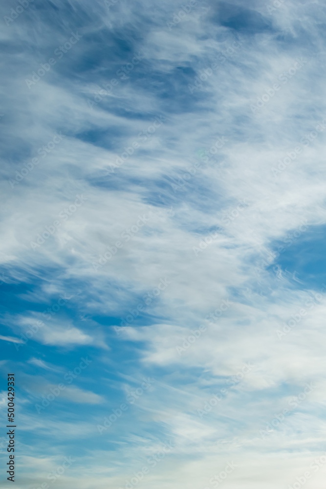 Blue sky background. Light cirrus clouds in rays of sun on summer day. Blue sky background. Light cirrus clouds in rays of sun on summer day.