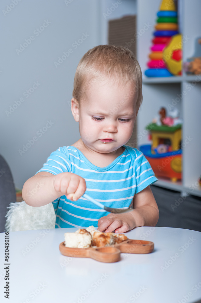Toddler boy eats on his own at table at home.. Toddler boy eats on his own at table at home..