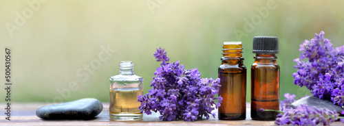 bottles of essential oil and  lavender flowers arranged on a wooden table on ...