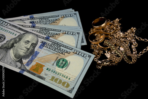 gold jewelry and a lot of dollars on a black background