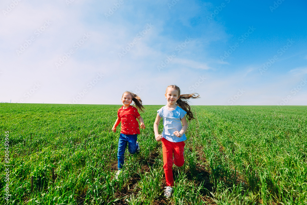 Running kids in green field during summer.