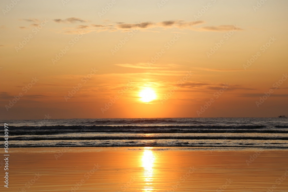 Sunrise on the beach. Vibrant colors of the sun, reflections in the water and sand. Beautiful scenery of nature. Red sky, rising sun, lots of light in the ocean waters. Magnificent marine sunset scene
