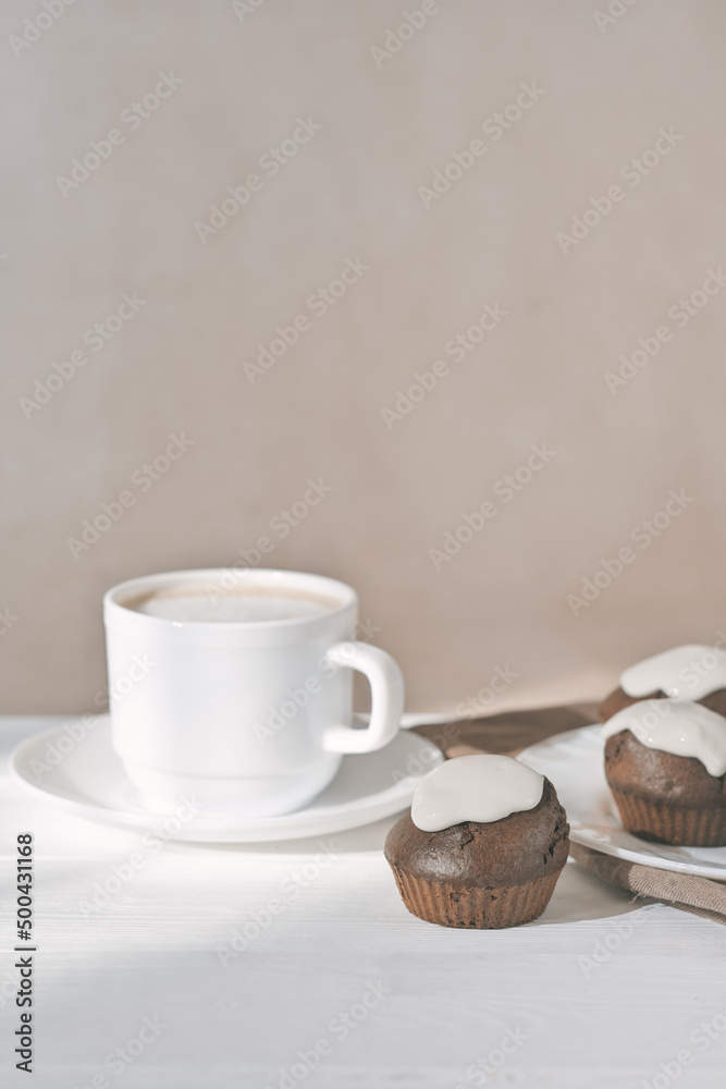 cup of latte coffee and fresh baked cupcakes with icing. chocolate muffins home baked in the morning. vertical shot. cup of latte coffee and fresh baked cupcakes with icing. chocolate muffins home baked in the morning. vertical shot.
