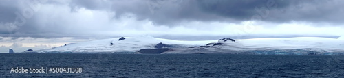 Panorama of a glacier meeting the Southern Ocean at the base of rugged mountains in Antarctica © Angela