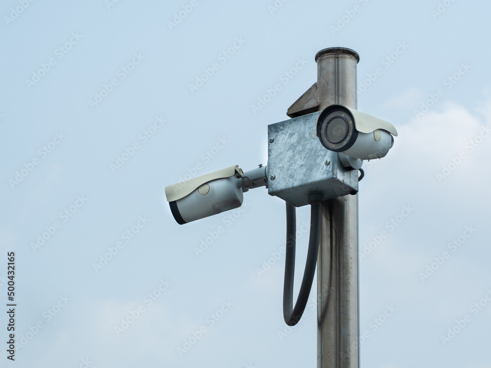 Old pair of surveillance camera or CCTV installed on poles in a public park. Old pair of surveillance camera or CCTV installed on poles in a public park.