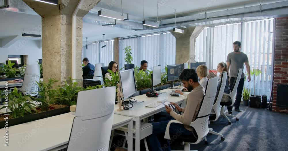People IT developers sitting at computers and working. Support office employees. Man coming and helping in work to colleague. Male and female talking and discussing. Team of startuppers.