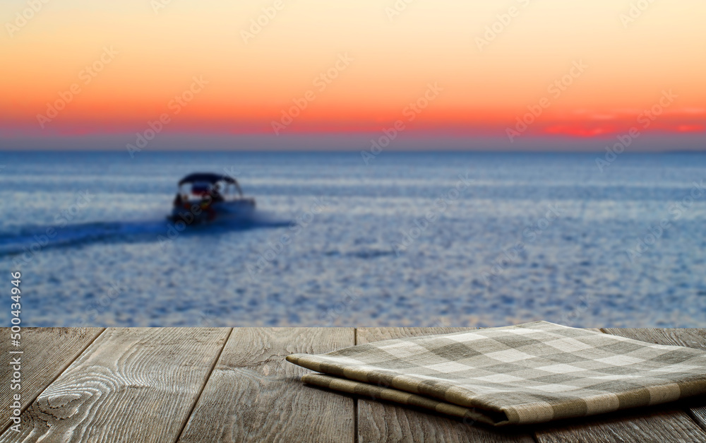 An empty brown wooden table. Blurred background with sunset on the sea.