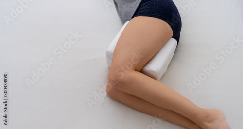 Woman using knee support pillow for correct sleeping position