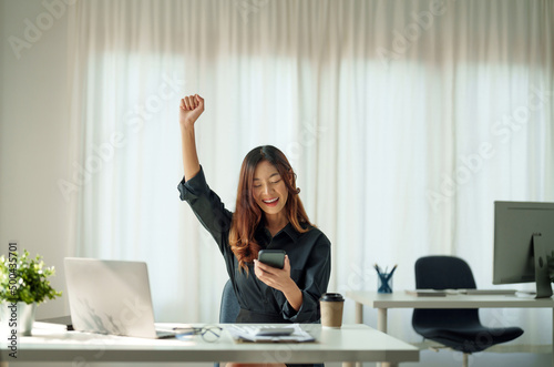 Portrait of happy young business asian woman celebrating success with arms up. positive expression, sucess in business concept photo