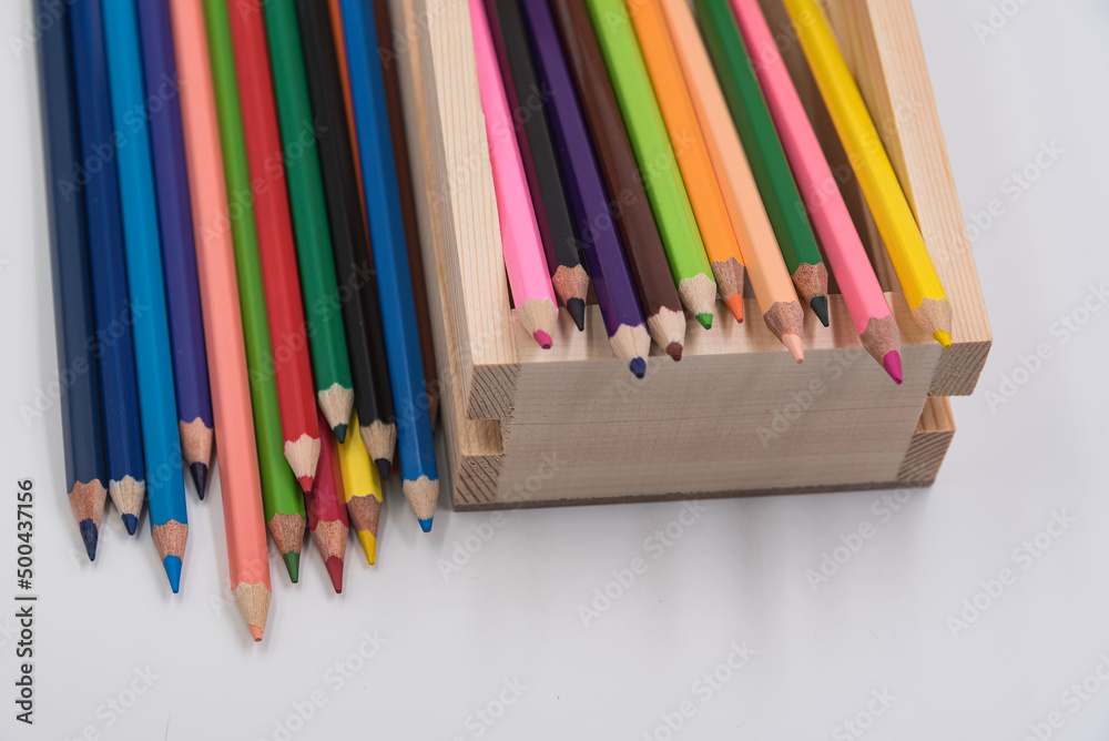 color wood pencil put in wooden box and spread on white background.