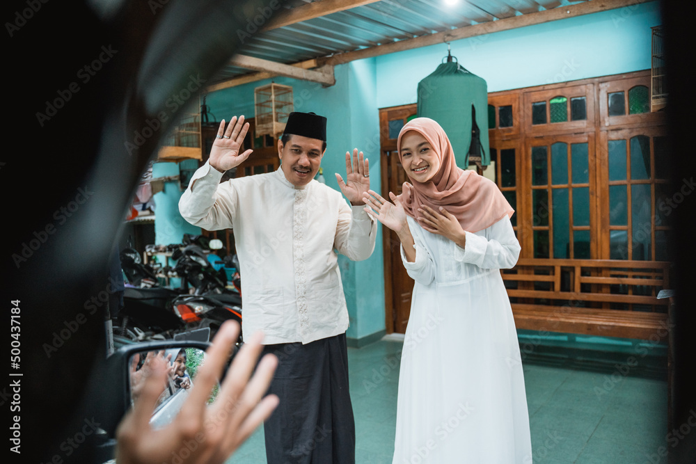 muslim happy family welcoming guest to their house during eid mubarak idul fitri celebration muslim happy family welcoming guest to their house during eid mubarak idul fitri celebration
