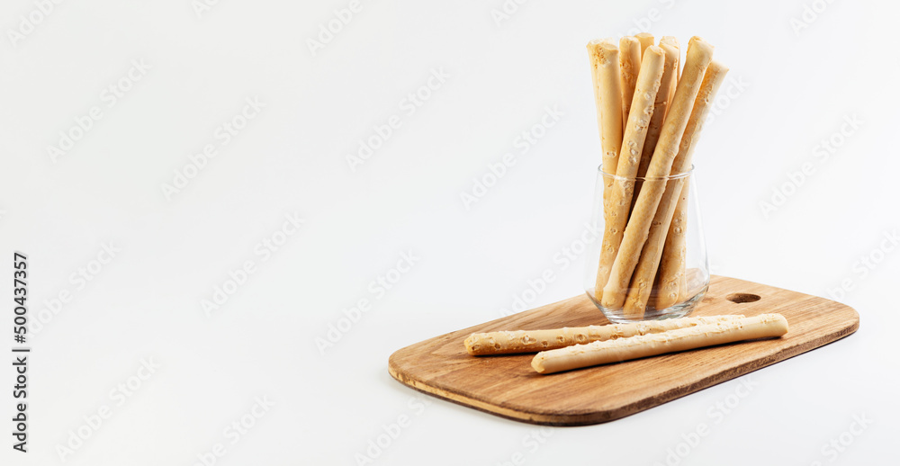 bread sticks in a glass on a wooden board, banner, white background