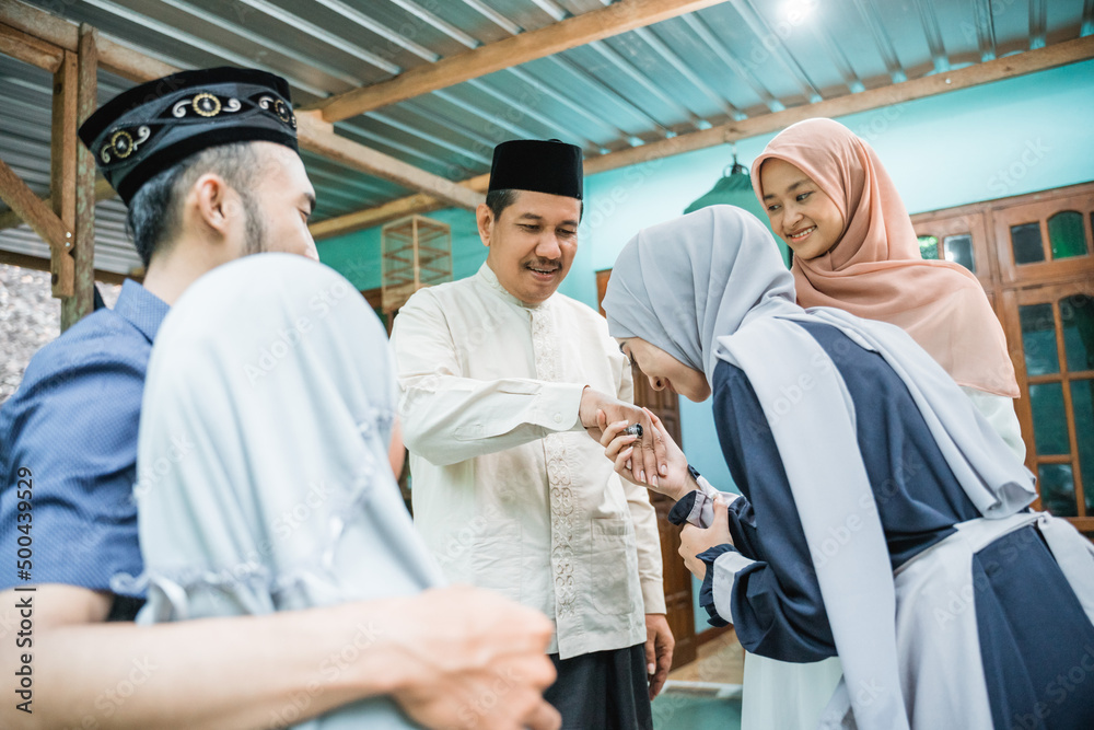 children visiting their parent during eid mubarak idul fitri at home. asian muslim family shake hand saying sorry and ask blessing children visiting their parent during eid mubarak idul fitri at home. asian muslim family shake hand saying sorry and ask blessing