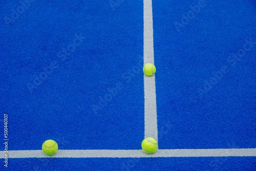 racket sports, three balls on the lines of a blue paddle tennis court © VicVaz